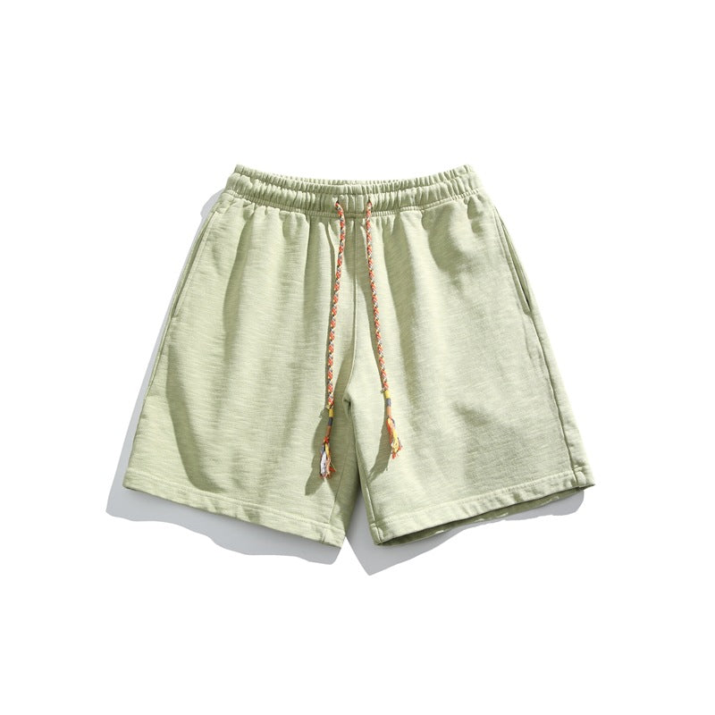 Light yellow-green knit shorts flat lay with elastic waist and braided multicolor drawstring
