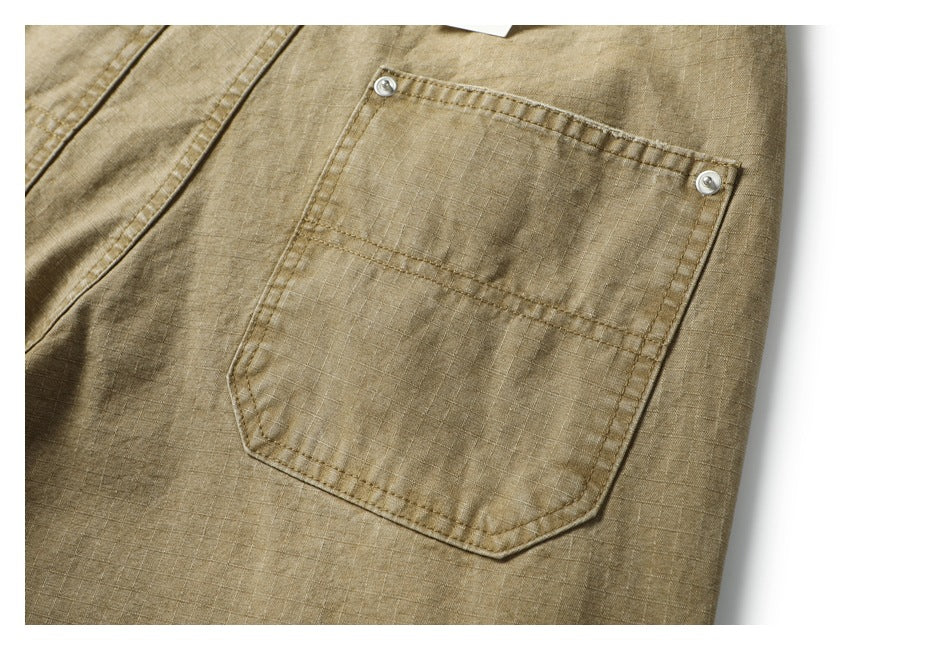 Close-up of a tan garment pocket with two metal buttons and visible stitching.