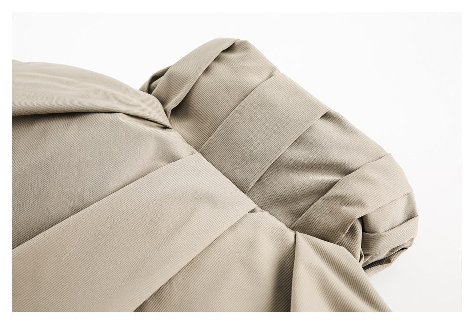 Close-up of overlapping panels and a curved seam on a light taupe ribbed garment.