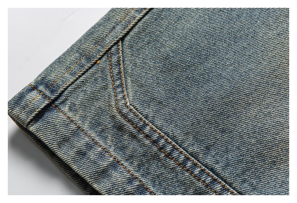 Close-up of washed blue denim with parallel orange stitching along a folded seam.