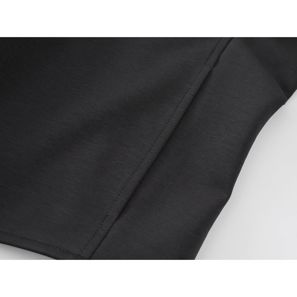 Close-up of charcoal jacket fabric and a stitched seam near the hem.