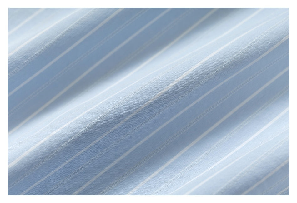 Macro view of light blue fabric with narrow white pinstripes and stitched lines.