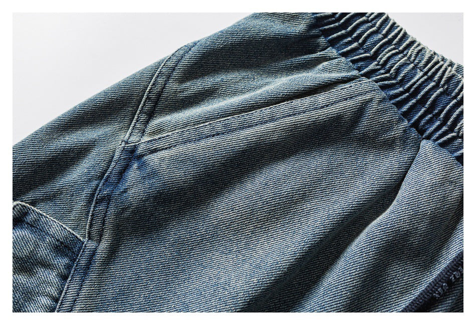 Close-up of blue denim shorts showing a stitched seam beside the gathered waistband.
