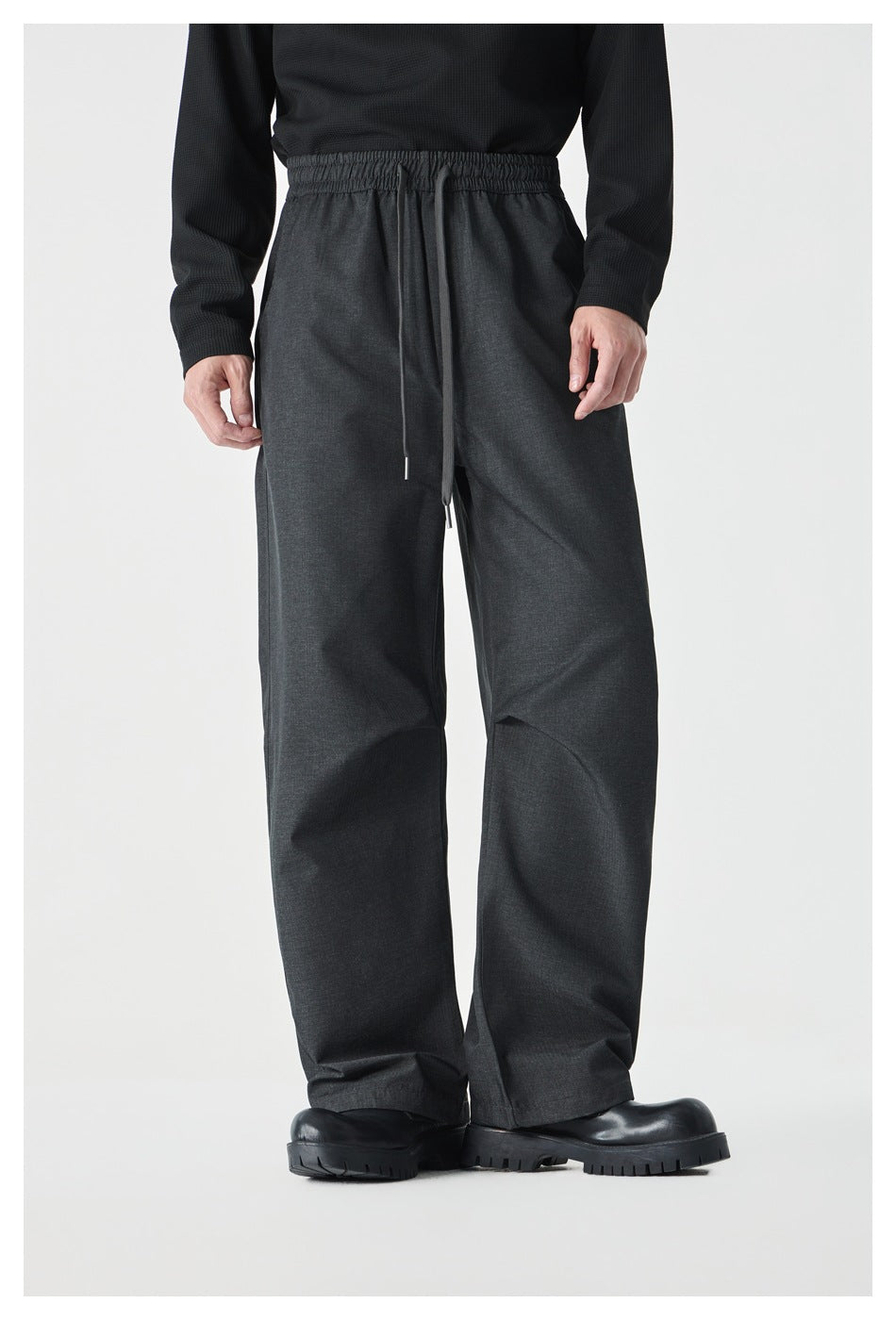Front view of a model wearing charcoal wide-leg pants with an elastic drawstring waist.