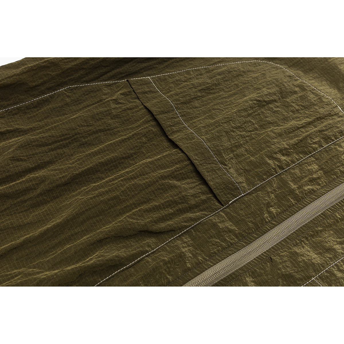 Close-up of an olive jacket panel with a stitched pocket, contrast seams and zipper edge.