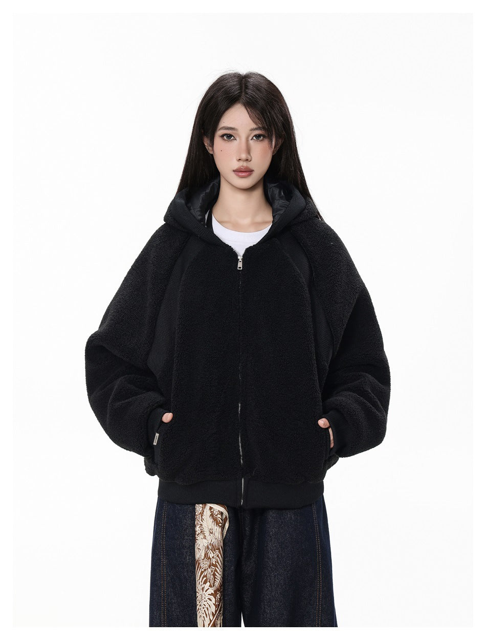 Model wearing a black plush zip-up hoodie with the hood down, raglan sleeves, and ribbed cuffs and hem.