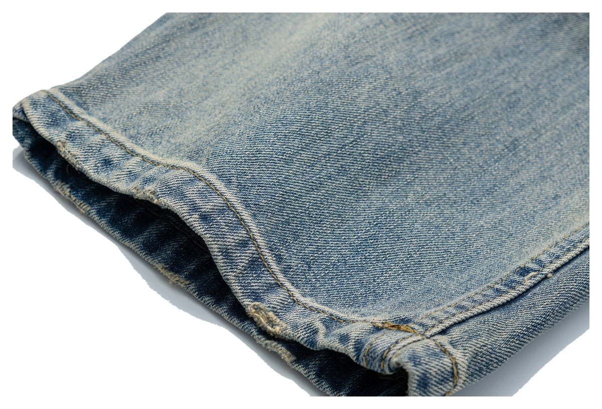 Close-up of a faded blue denim jeans leg and stitched hem.