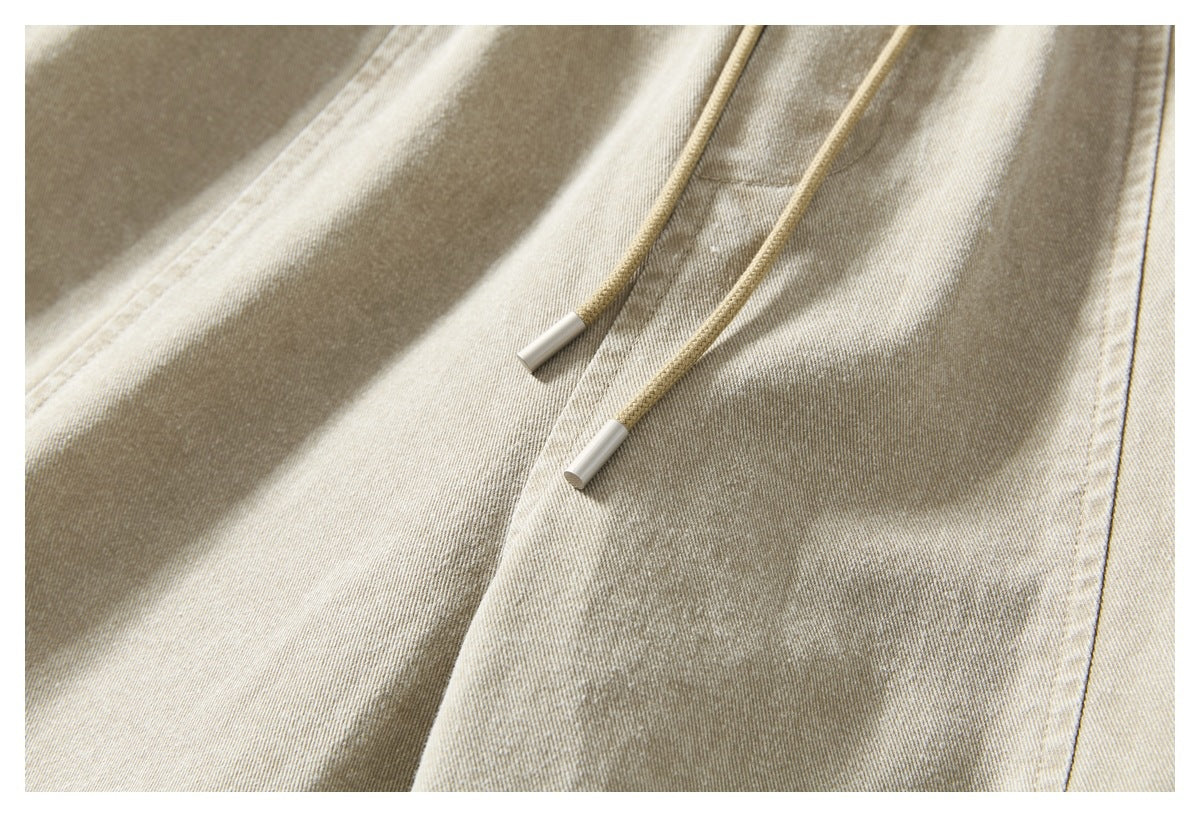 Close-up of two khaki drawstrings with silver-colored tips against the garment fabric.
