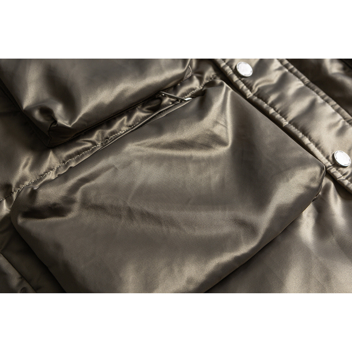 Close-up of a large pocket and metal snaps on a glossy taupe jacket.