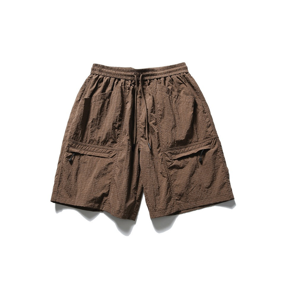 Brown crinkled grid-pattern drawstring shorts with two zip thigh pockets, flat lay front view