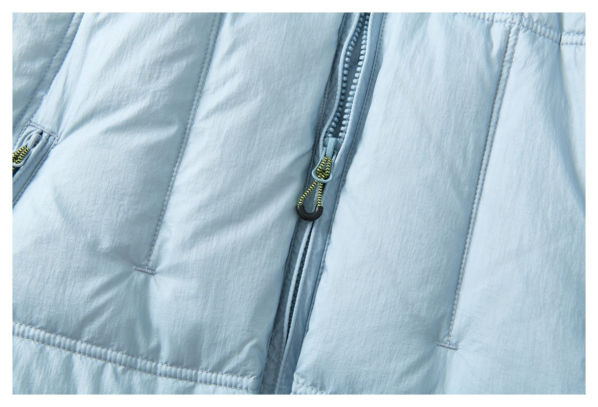 Close-up of a pale blue jacket's center zipper, cord pull and stitched front pockets.