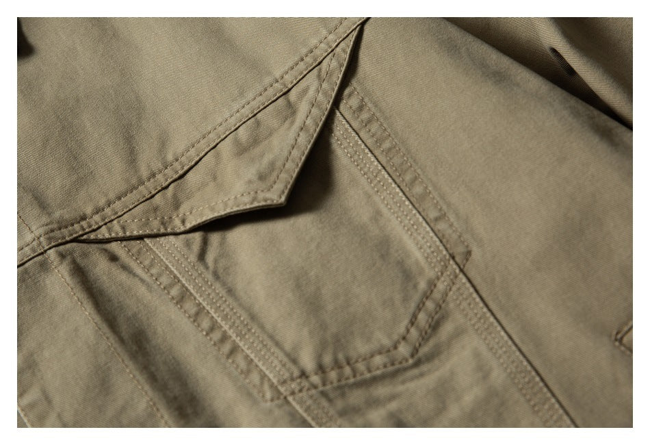 Close-up of a stitched patch pocket and flap on an olive-khaki garment.