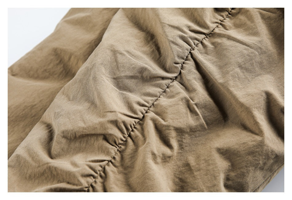 Close-up of a tan garment with gathered stitching along a curved seam.