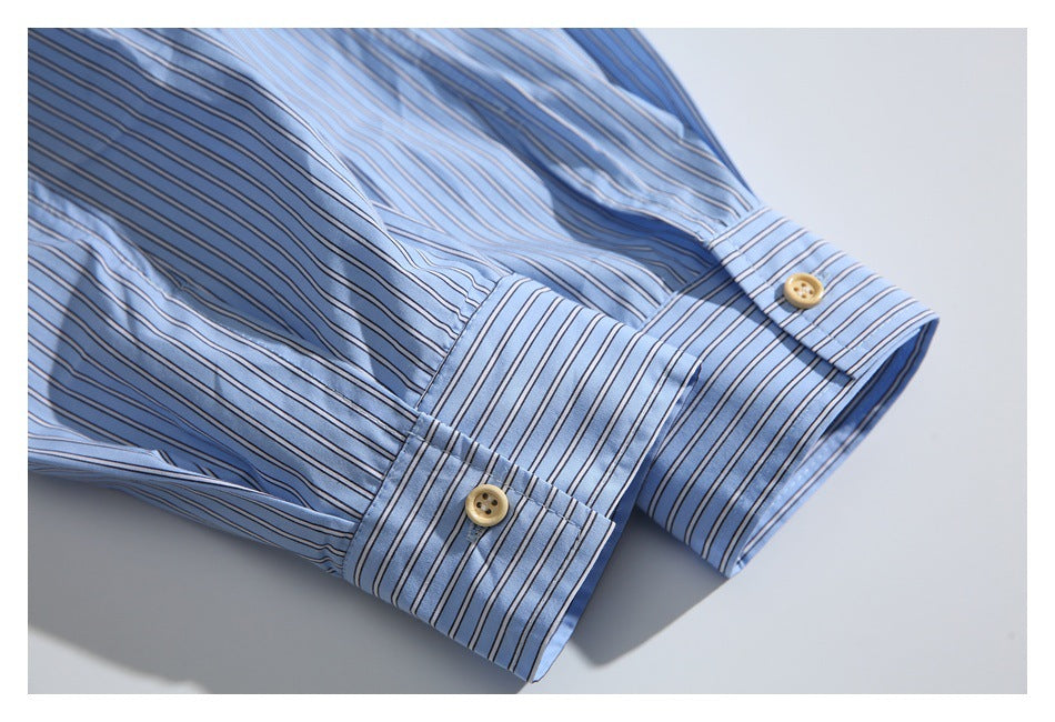 Close-up of a light blue striped shirt sleeve and buttoned cuff with tan buttons.