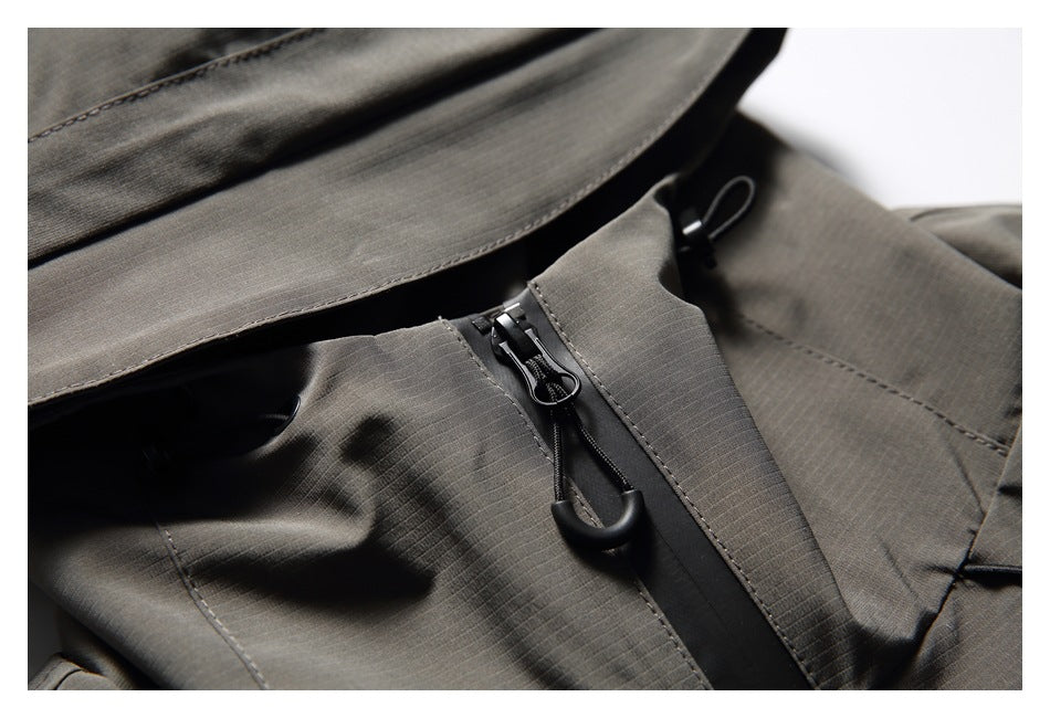 Close-up of a charcoal-gray jacket's hood brim, high collar and black front zipper with pull.