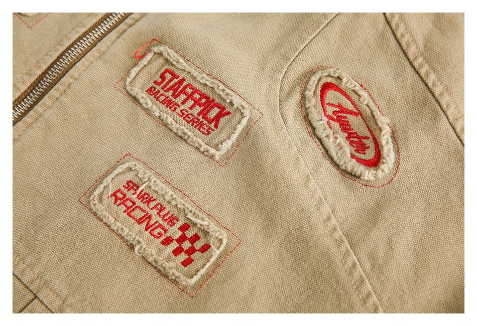 Close-up of embroidered red-and-cream patches on the tan jacket beside the zipper.