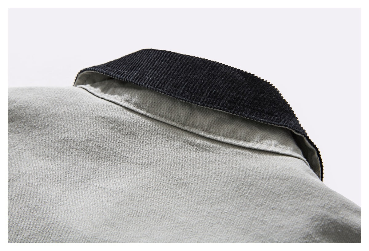 Close-up of a light gray garment edge with wide black ribbed trim.
