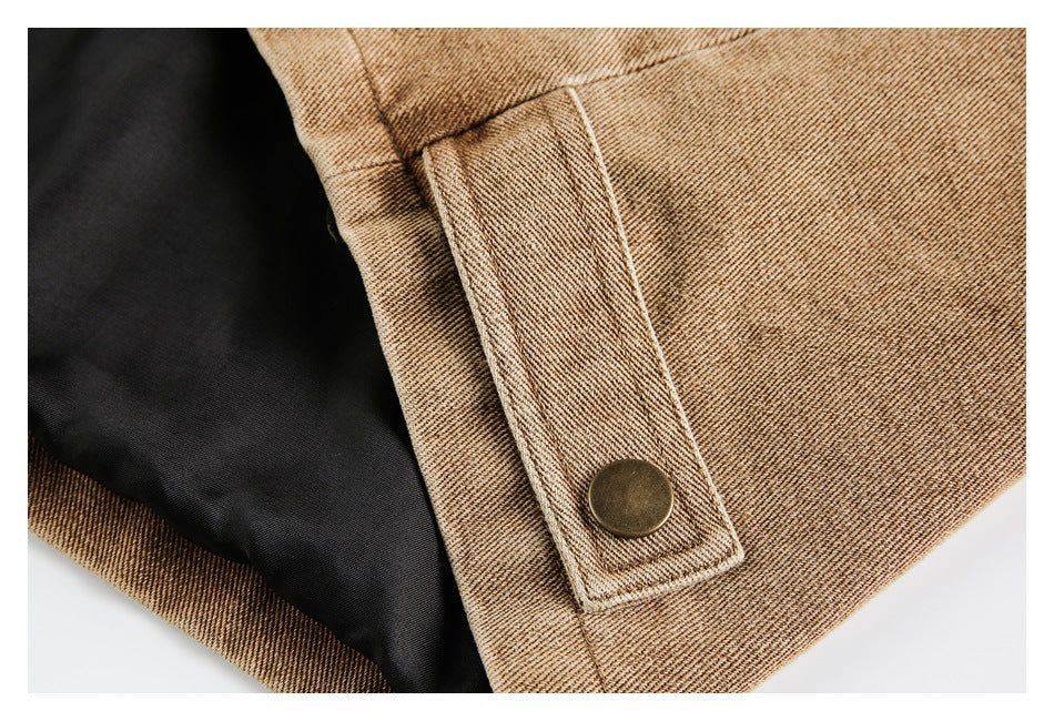 Close-up of a tan jacket cuff with a brass-colored snap tab and black lining.