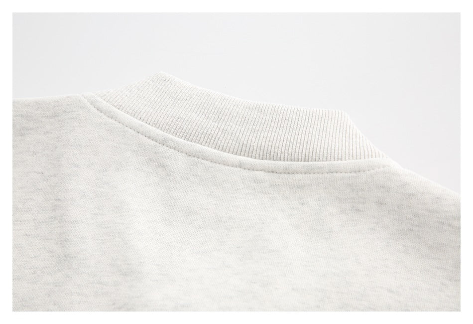 Close-up of the ribbed crew neckline and shoulder seam on a light heather-gray sweatshirt.