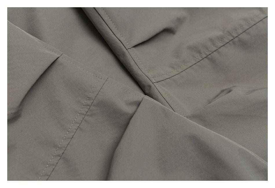 Close-up of gray-olive garment panels with intersecting stitched seams.