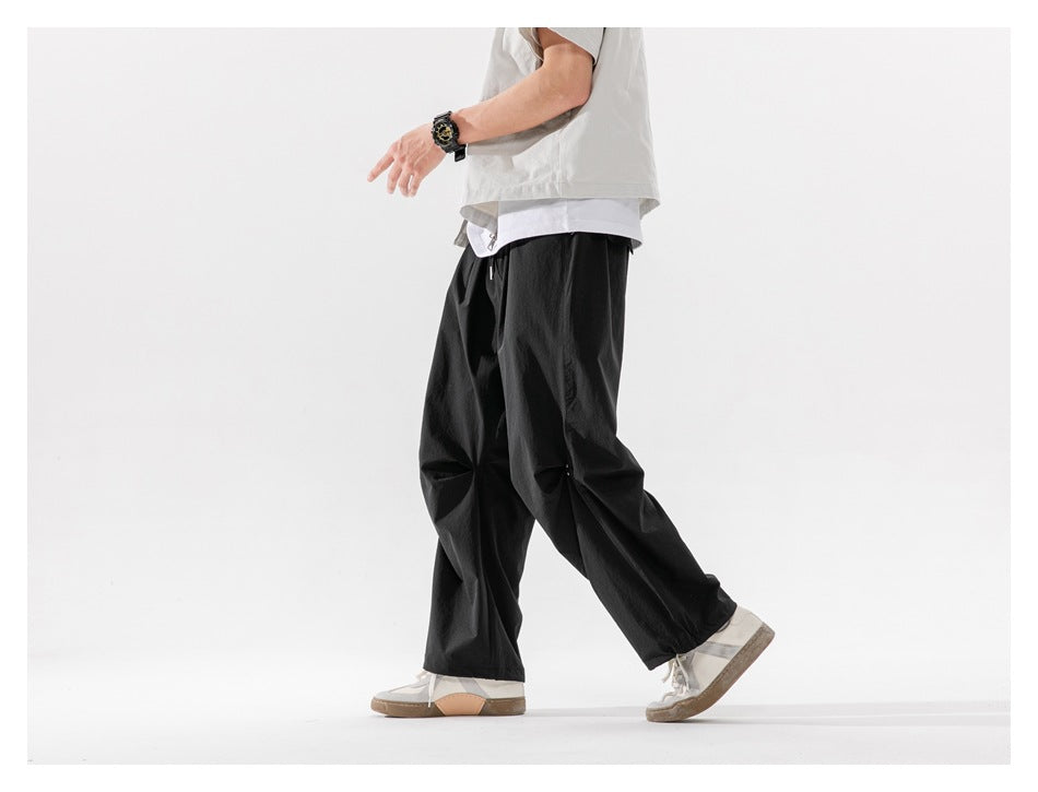 Side view of a model walking in loose black drawstring trousers.