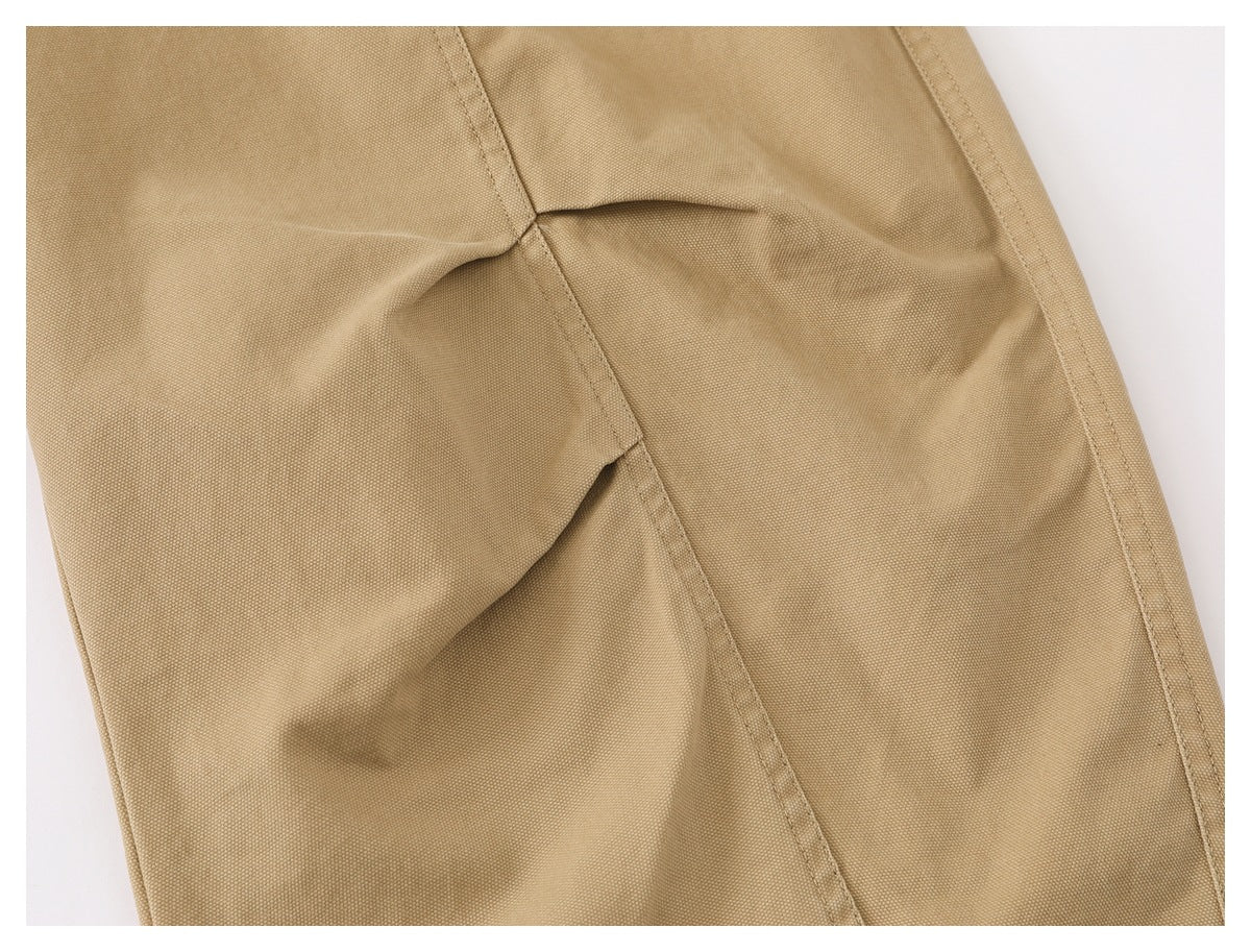 Close-up of tan garment fabric with stitched seams and a folded pleat.