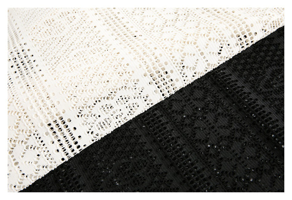Close-up of white and black openwork lace fabric with repeating geometric patterns.