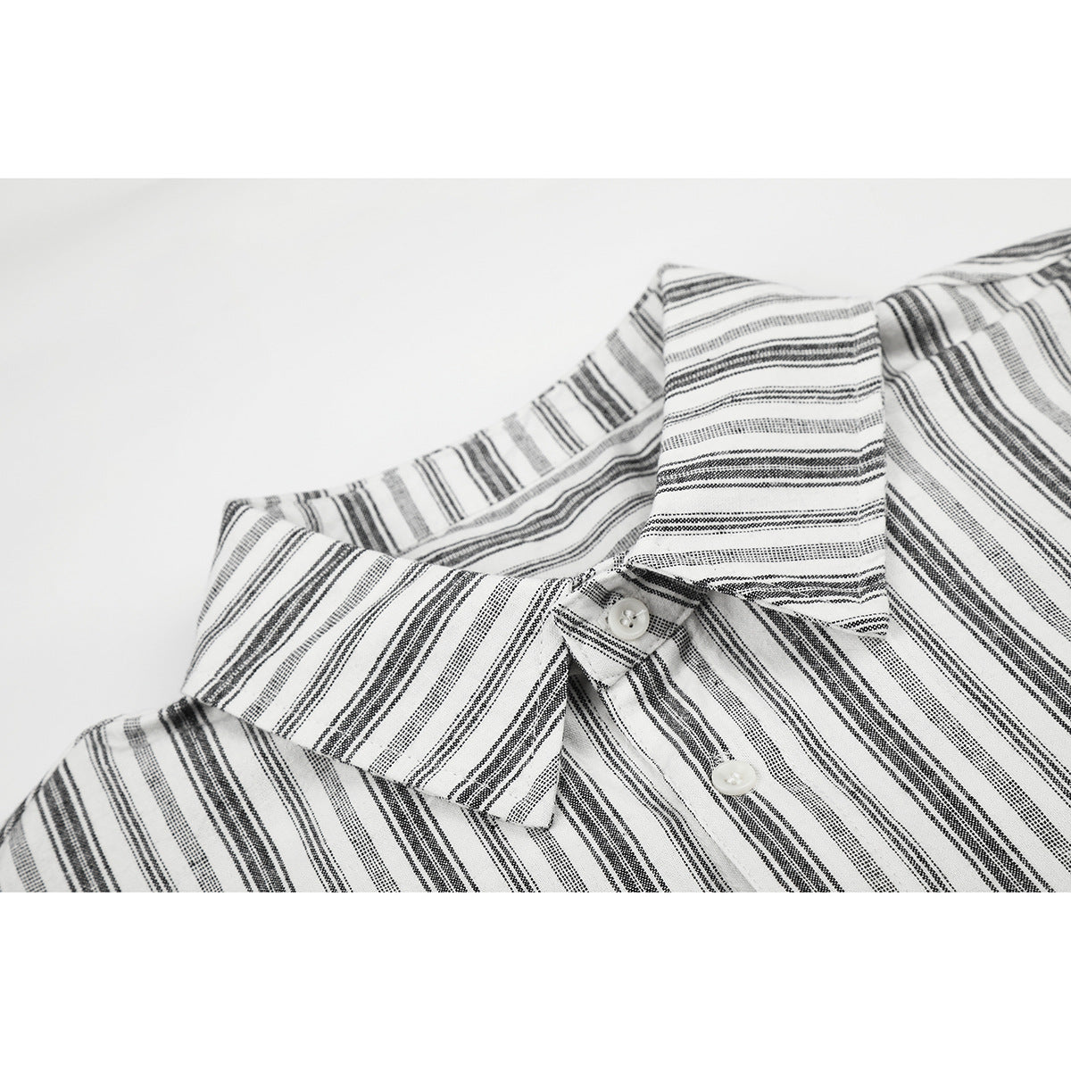 Close-up of a white button-up shirt with narrow black stripes, showing the pointed collar and buttons.
