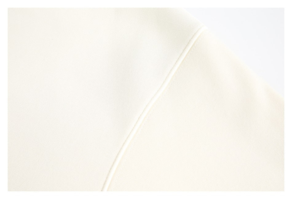 Close-up of a diagonal stitched seam across ivory garment fabric.