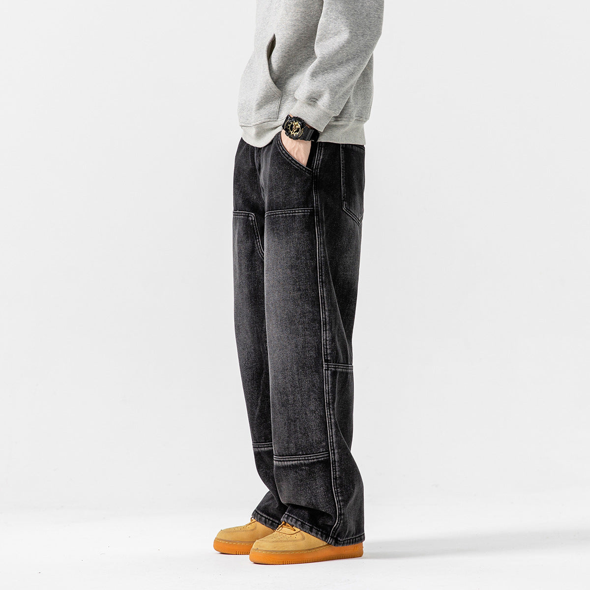 Side view of a model wearing loose black washed panel-seam jeans and a gray sweatshirt.