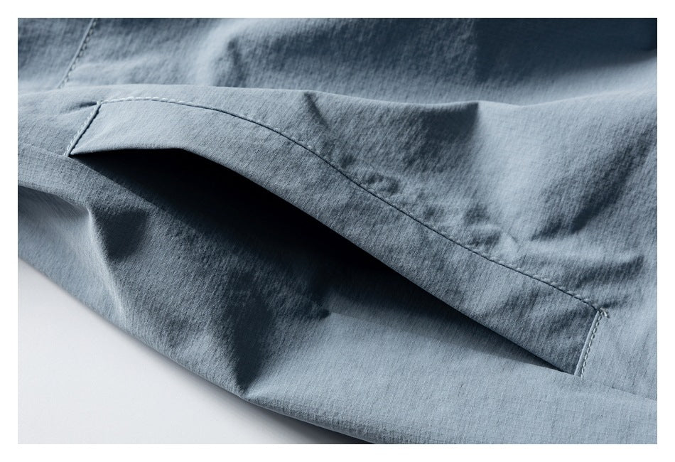 Close-up of a blue-gray garment hem with visible stitching and overlapping fabric.
