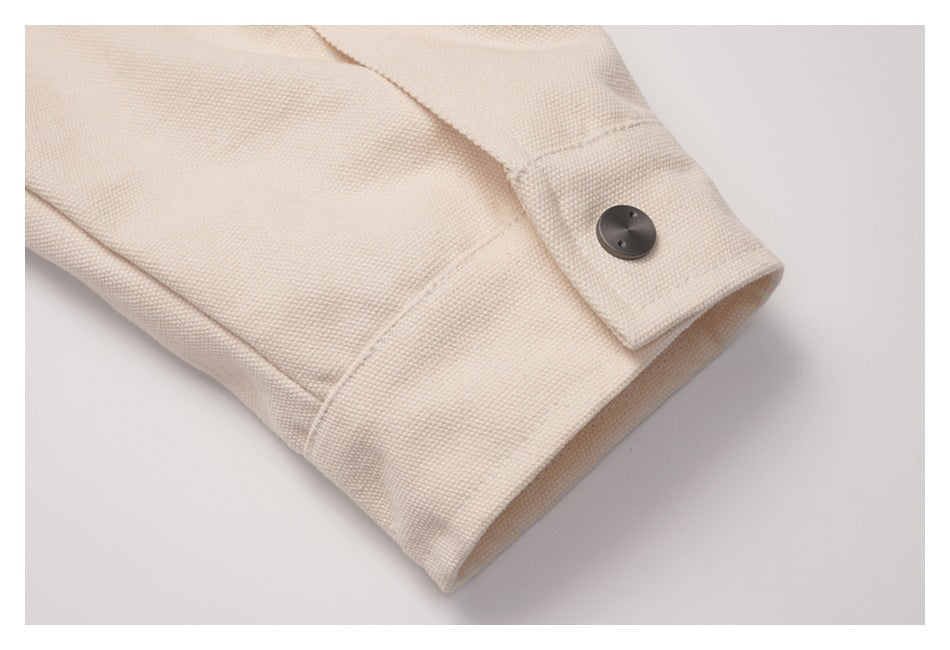 Close-up of a cream coat sleeve cuff with a dark button and visible stitching.