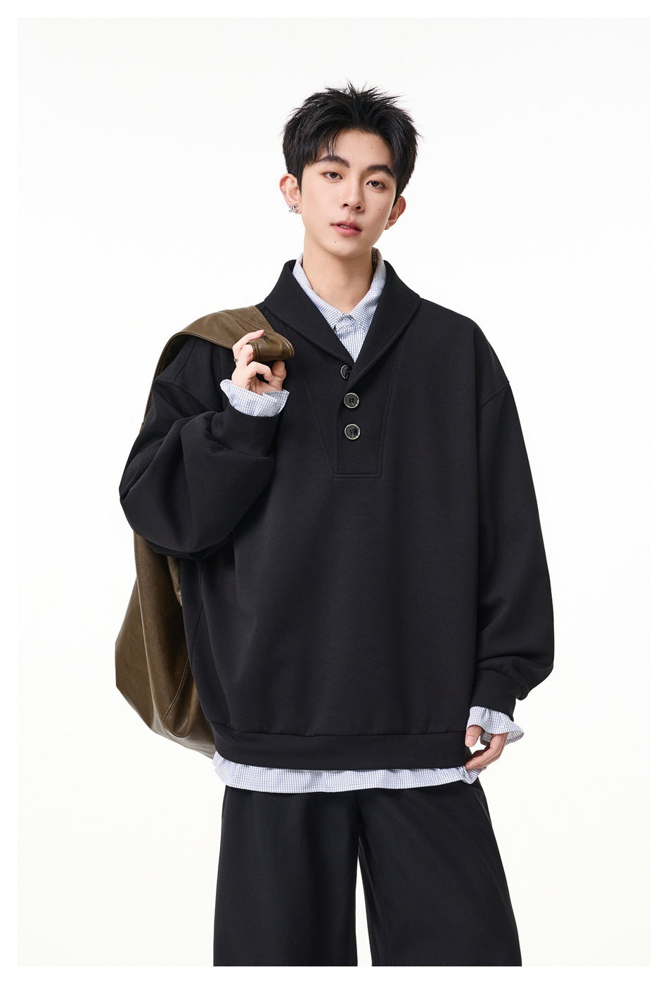 Model wearing a black oversized pullover with a wide collar and three-button placket.