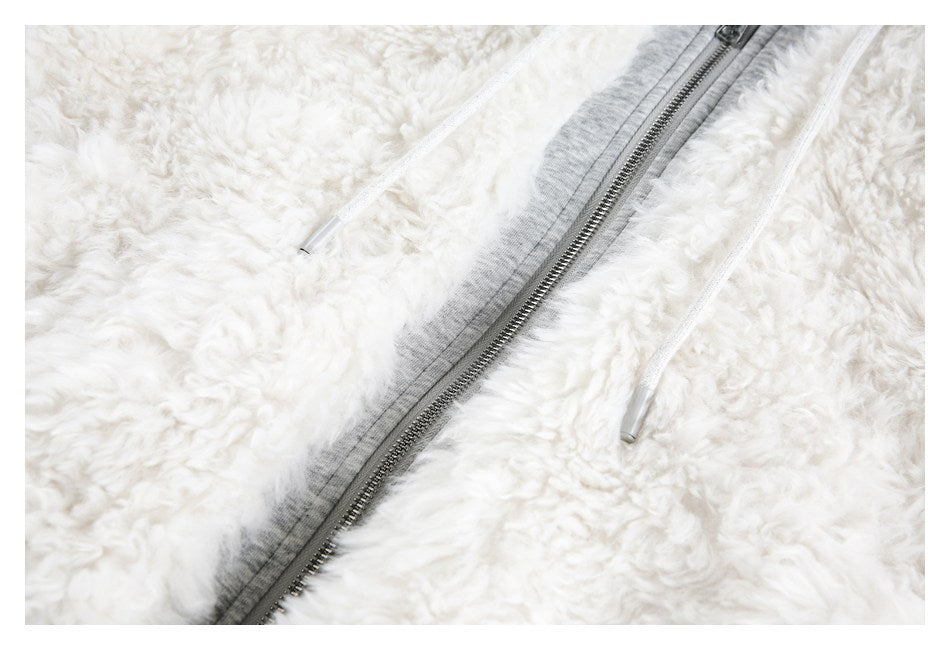 Close-up of a metal zipper and white drawstrings against the jacket's white fluffy surface.