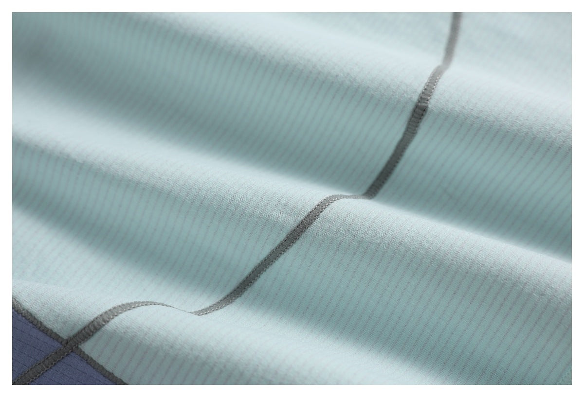 Close-up of pale aqua striped fabric with gray overlock stitching and a small section of lavender fabric.