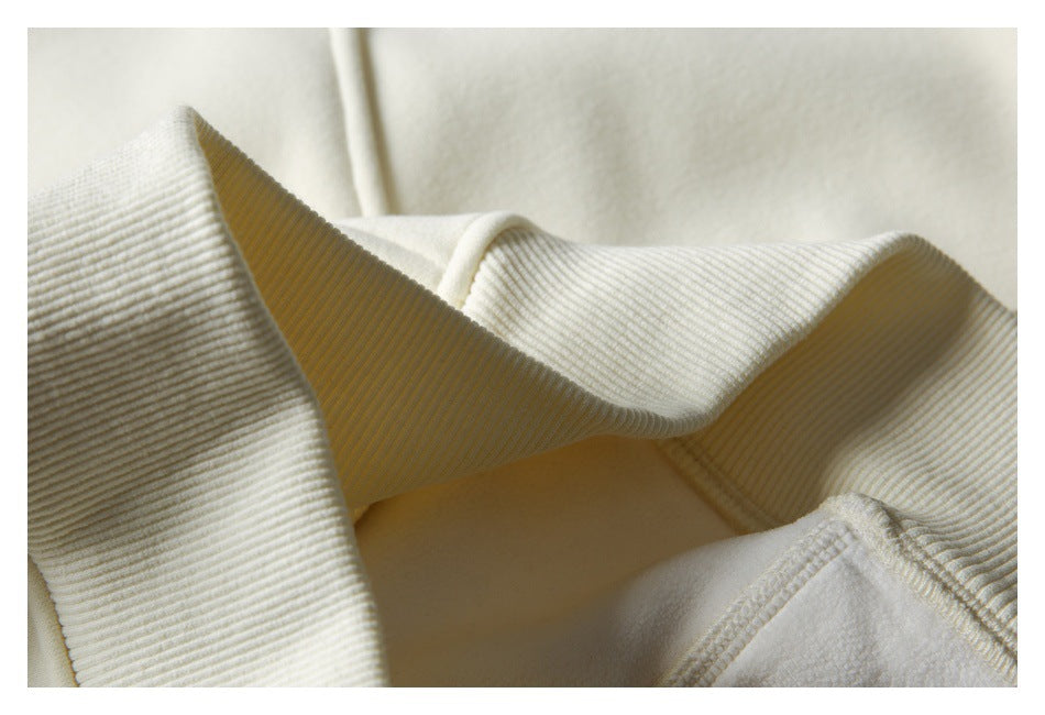 Close-up of cream sweatshirt fabric and ribbed trim, showing the stitching and folded construction.