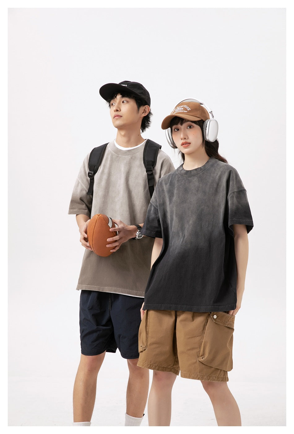 Two models wear oversized T-shirts in taupe-gray and charcoal, shown together.