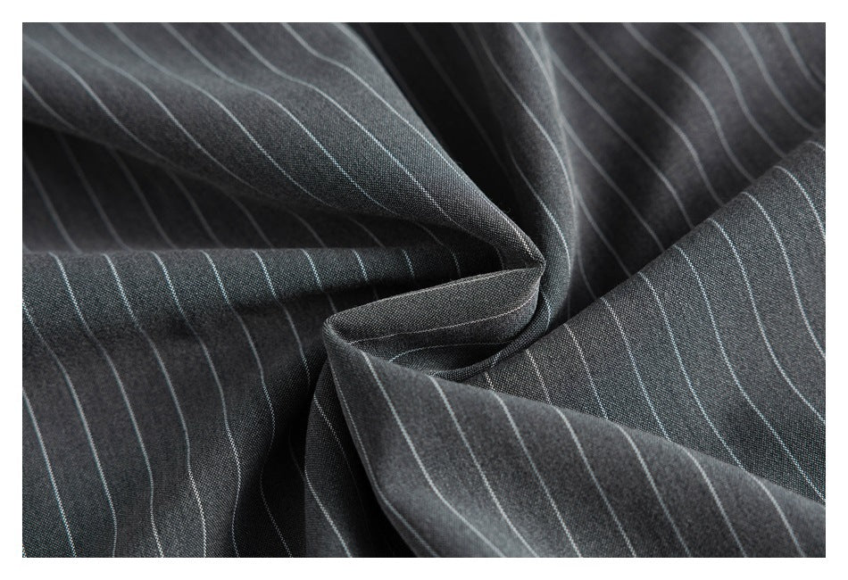 Close-up of charcoal fabric with thin light pinstripes gathered into soft folds.
