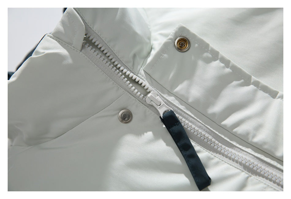 Close-up of a white jacket's front zipper, dark pull tab, and metal snaps.