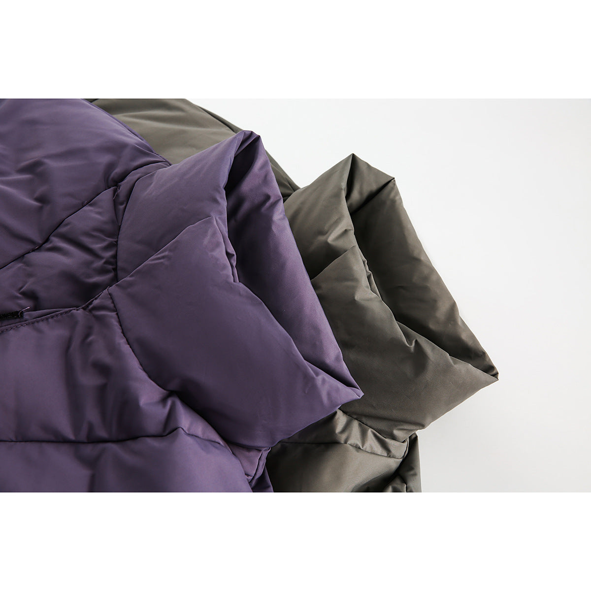 Close-up of overlapping purple and charcoal padded jacket panels with stitched quilting.