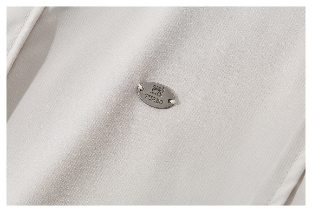 Close-up of a small oval TURBO badge attached to the light beige shirt fabric.