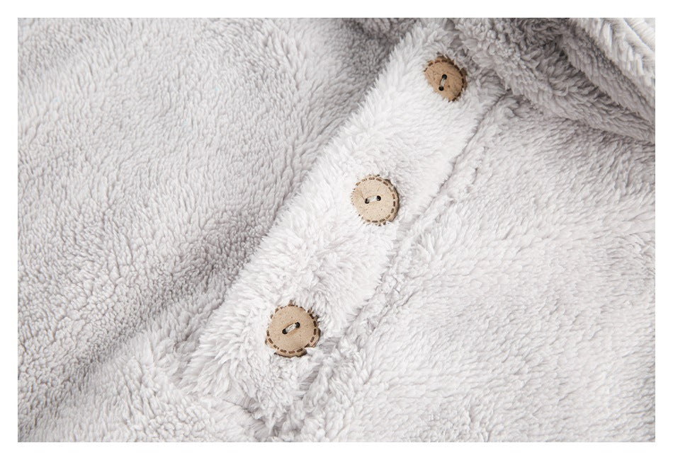 Close-up of a pale gray plush garment's front placket with three round tan buttons.