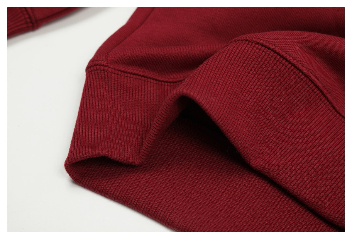 Close-up of burgundy sweatshirt ribbed hem and sleeve cuff folded together.