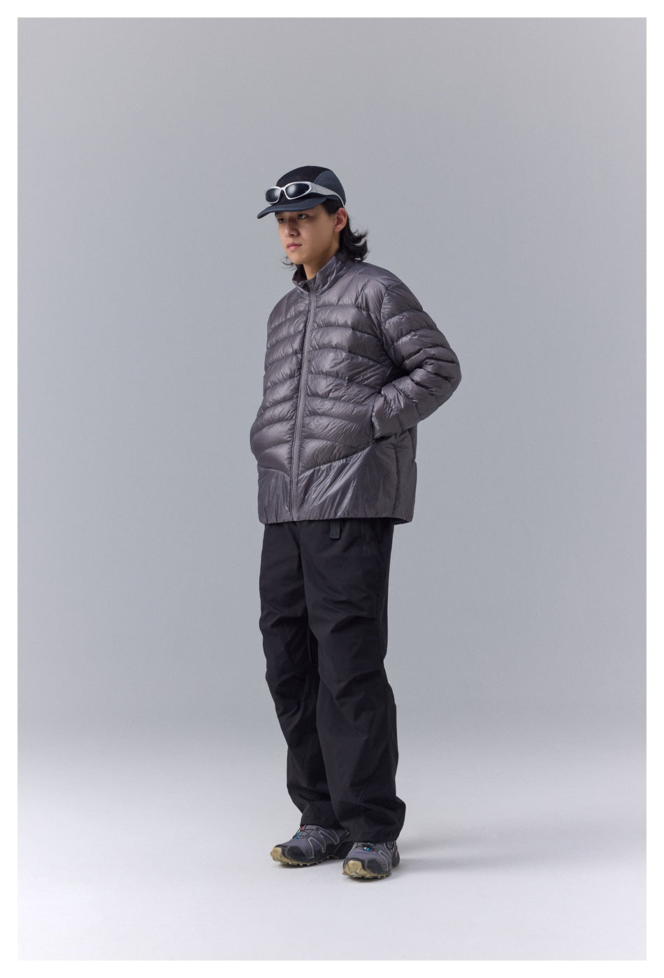 Model wearing a charcoal-gray quilted zip-front jacket with a stand collar and black trousers.