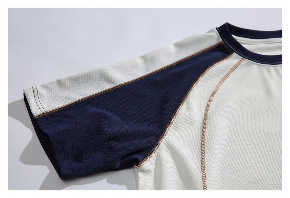 Close-up of the navy raglan sleeve panel and contrasting seams against the ivory shirt body.