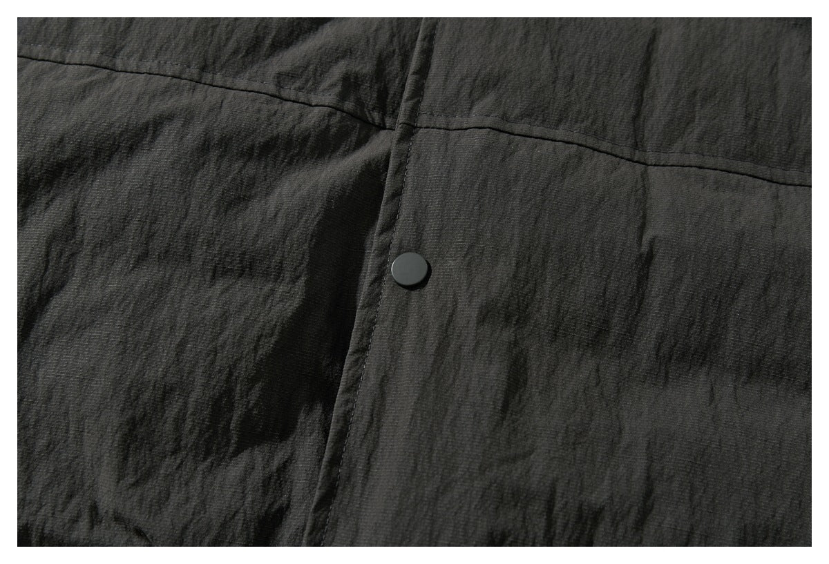 Close-up of the charcoal jacket’s textured shell, stitched seam, and black snap button.