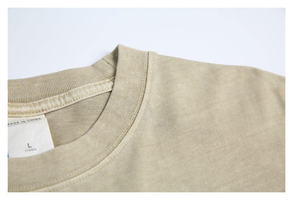 Close-up of the beige T-shirt's ribbed crew neck, shoulder seam, and partial size label.
