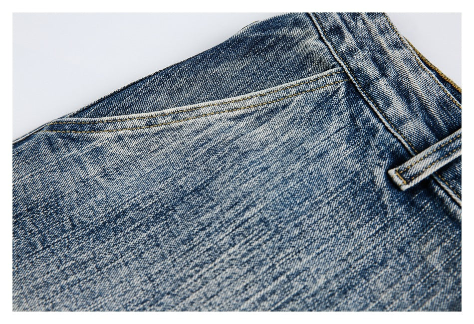 Close-up of faded blue denim showing a curved yoke seam and a belt loop near the waistband.
