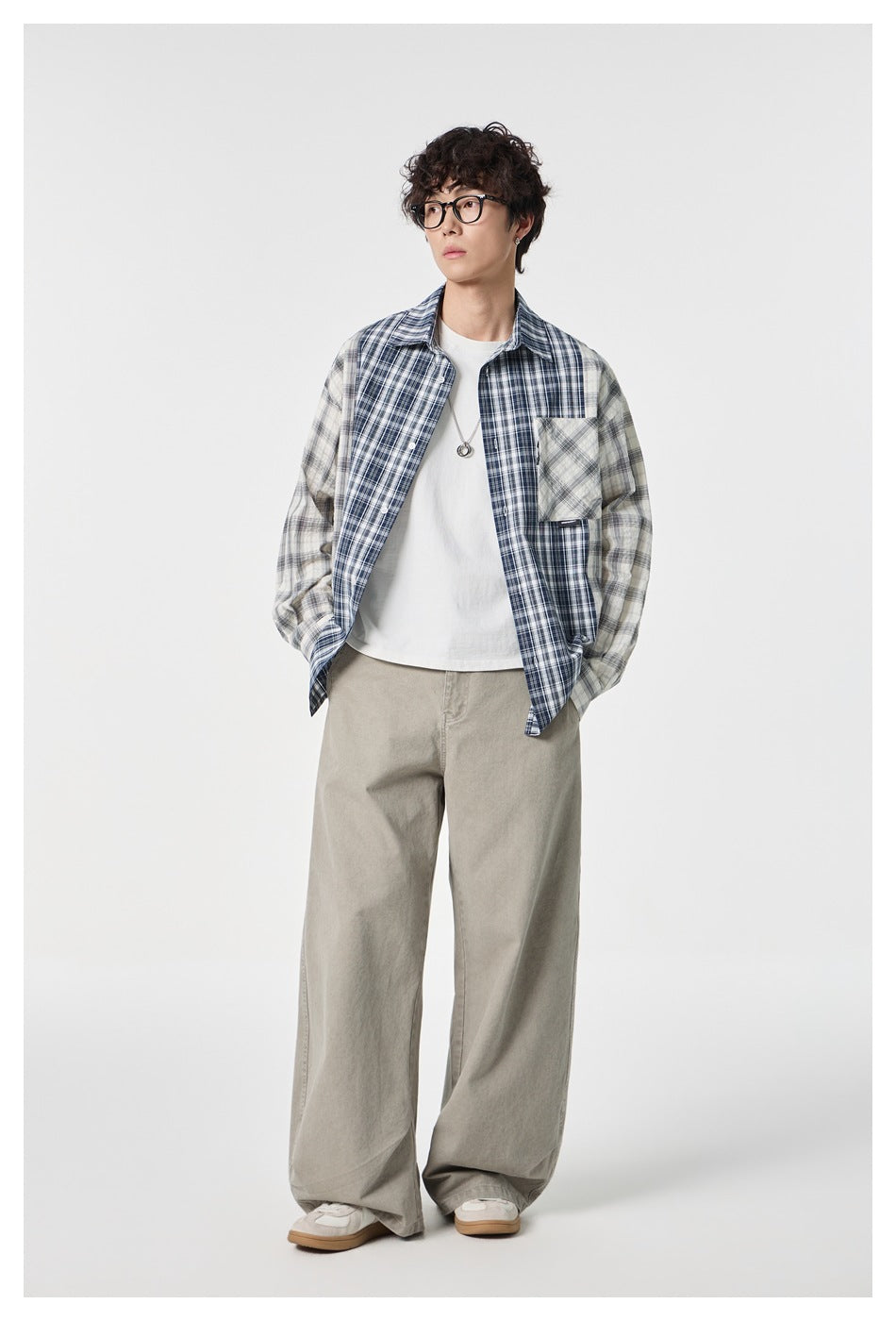 Model wearing open blue and white plaid patchwork shirt over a white tee with wide beige pants