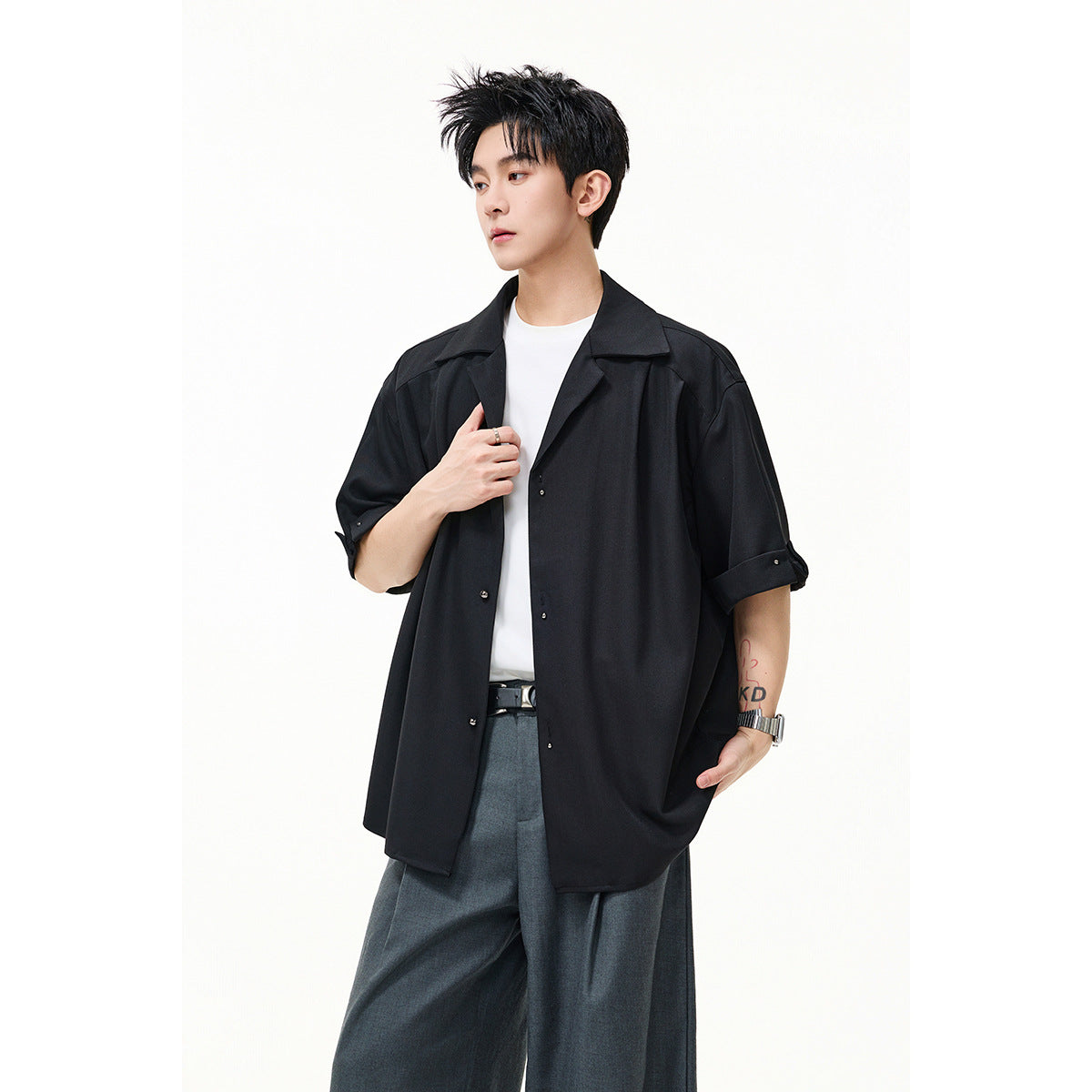 Closer view of a model wearing an oversized black button-up shirt with a wide collar and cuffed sleeves.